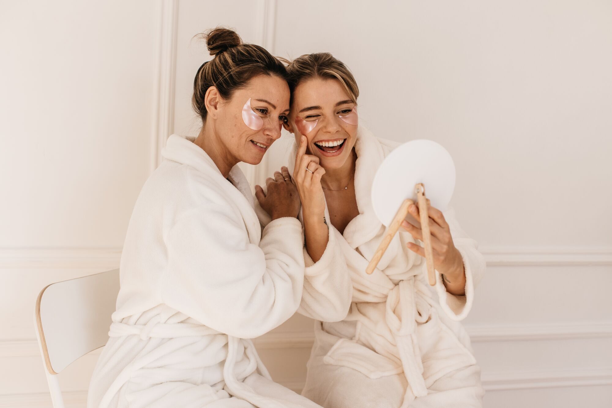 cute-caucasian-young-women-bathrobes-admire-themselves-while-looking-mirror-white-background-beauty-personal-care-skin-face-care-concept